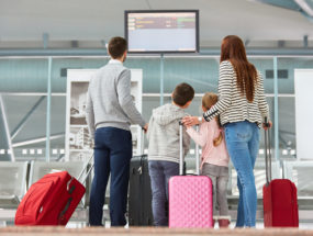 Family looks at the scoreboard in the airport terminal and looks for the right flight